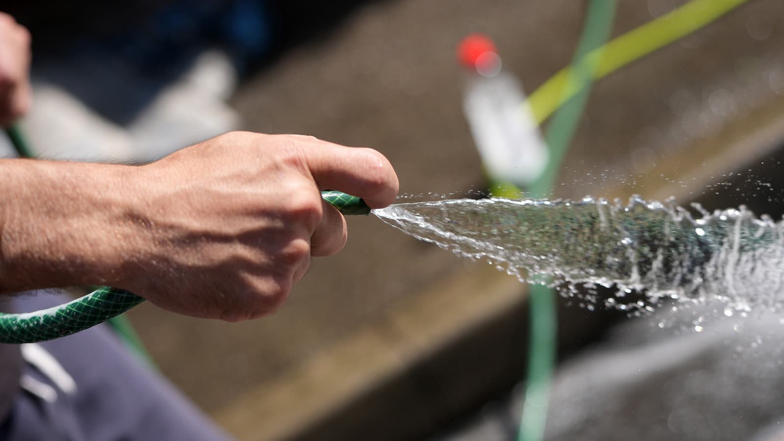 On the eve of a hosepipe ban a man uses a hosepipe to clean a carpet in the street