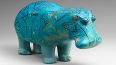 A glossy, blue statuette of a blue hippo. 
