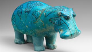 A glossy, blue statuette of a blue hippo. 