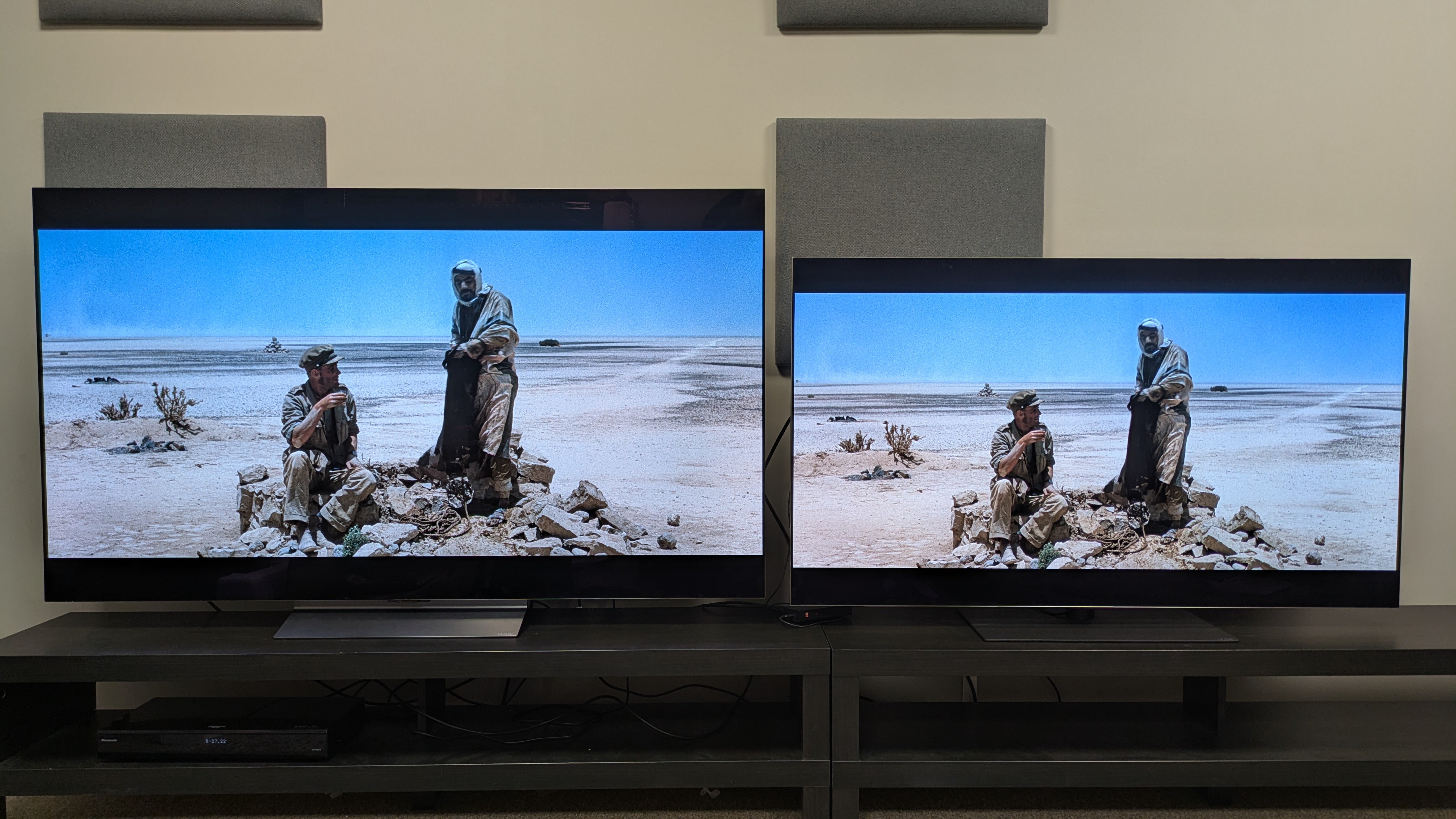 LG C6 (left) and LG G5 (right) with a scene from Lawrence of Arabia on-screen, featuring Lawrence and a guide in the desert. The whites of the sand look brighter on the G5