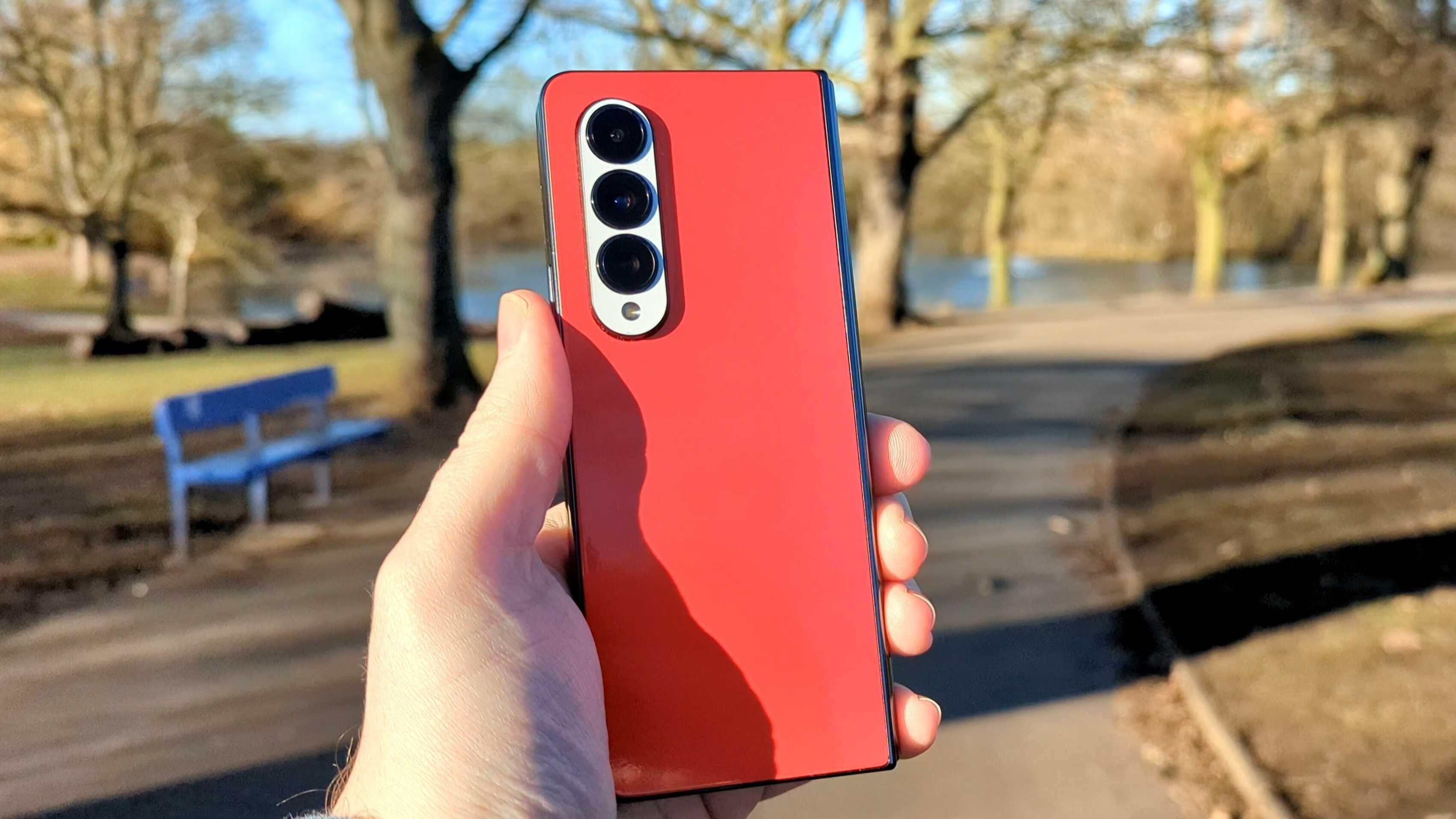 Samsung Galaxy Z Fold 4 with red skin on the back held up in the sun.