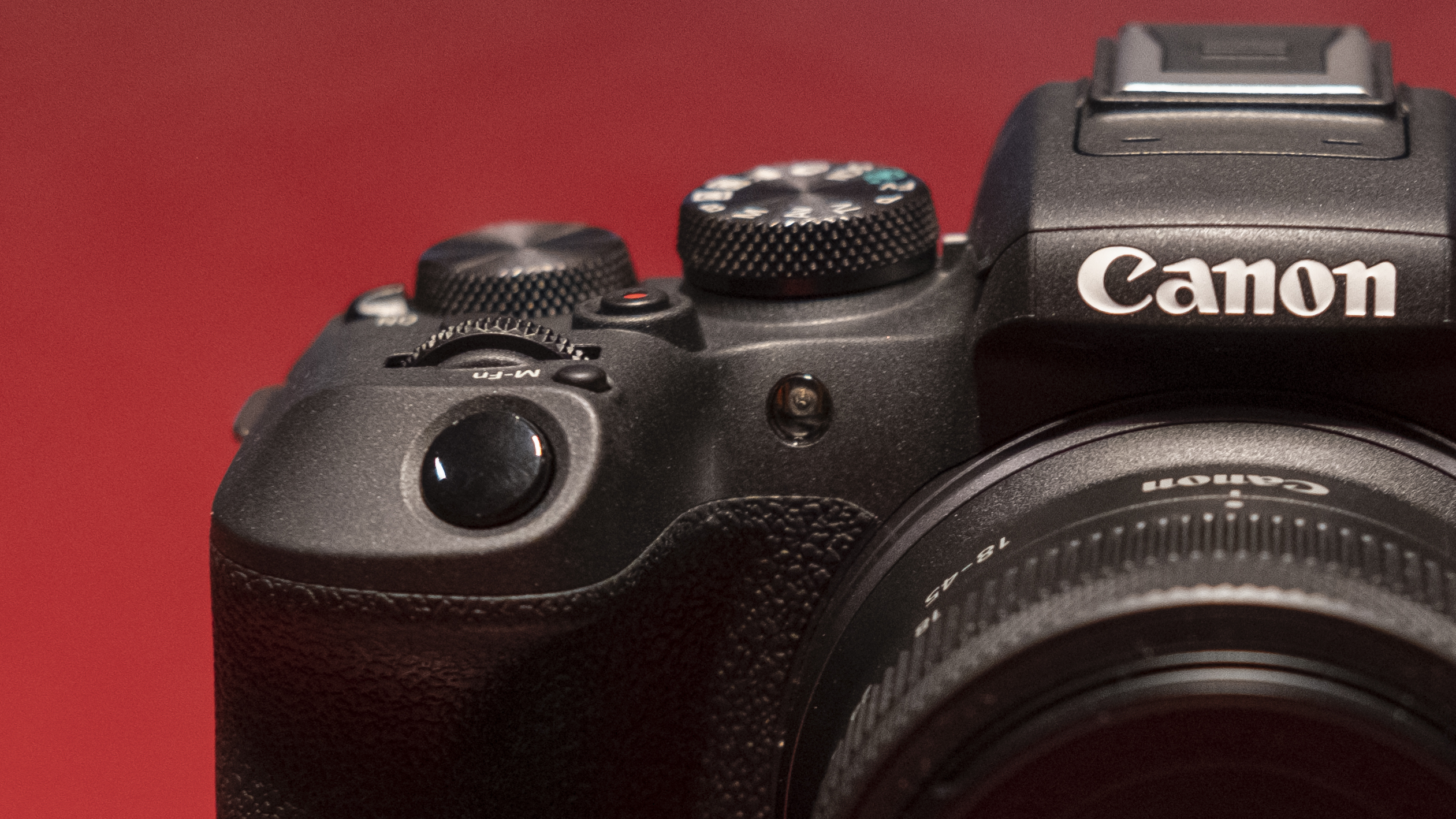 The Canon EOS R10 camera on a red surface