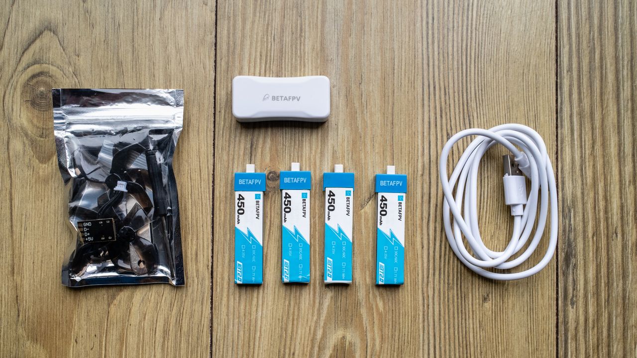 BetaFPX Cetus X drone kit accessories on wooden table including four batteries