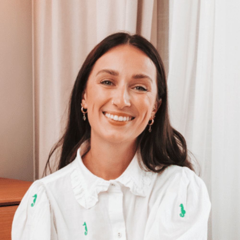 Headshot of a smiling brunette woman in a white shirt