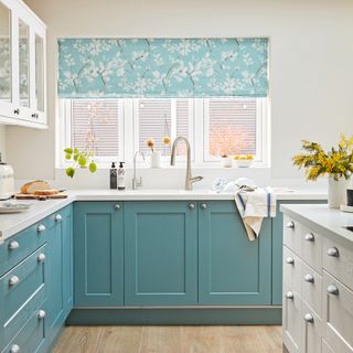 White kitchen with blue cabinetry and floral blinds