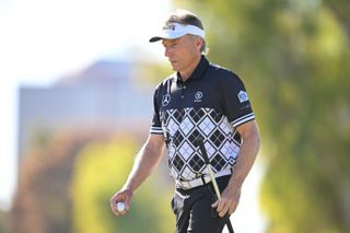 Bernhard Langer walks off the green holding his putter