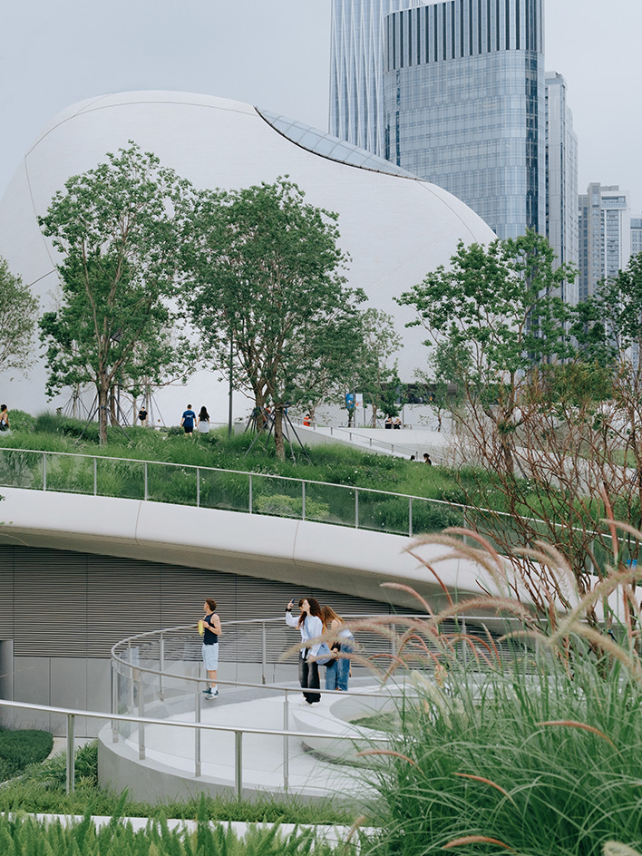 view of MAD Shenzhen Bay Culture Square, all white volumes and curves in a green park
