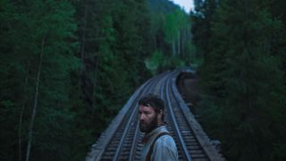 Joel Edgerton standing on train tracks in Train Dreams