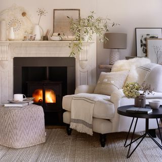 Cosy living room with white armchair and marble fireplace