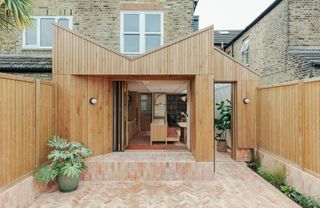 a timber extension with an outdoor brick floor - the patio bifold door is elevated on a platform