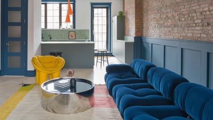 A living room with a navy blue sofa and a yellow chair