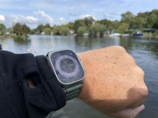 Apple Watch Ultra on a man's arm in front of a lake