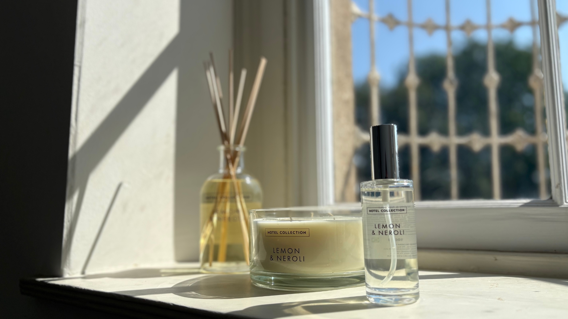 Aldi Lemon and Neroli Hotel Collection diffuser, room spray, and triple wick candle on a windowsill