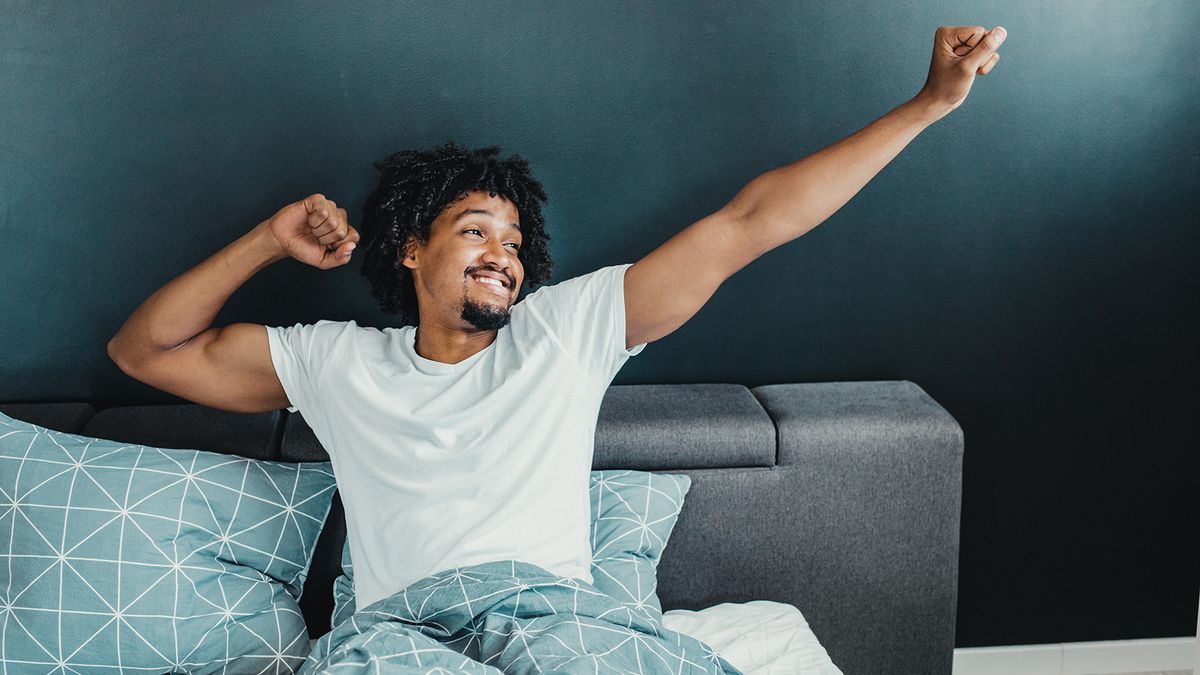 A man sitting up in bed stretching