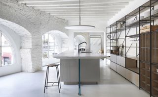 White boffi de padova showroom with a large island in the centre and connected shelf units on the right wall.