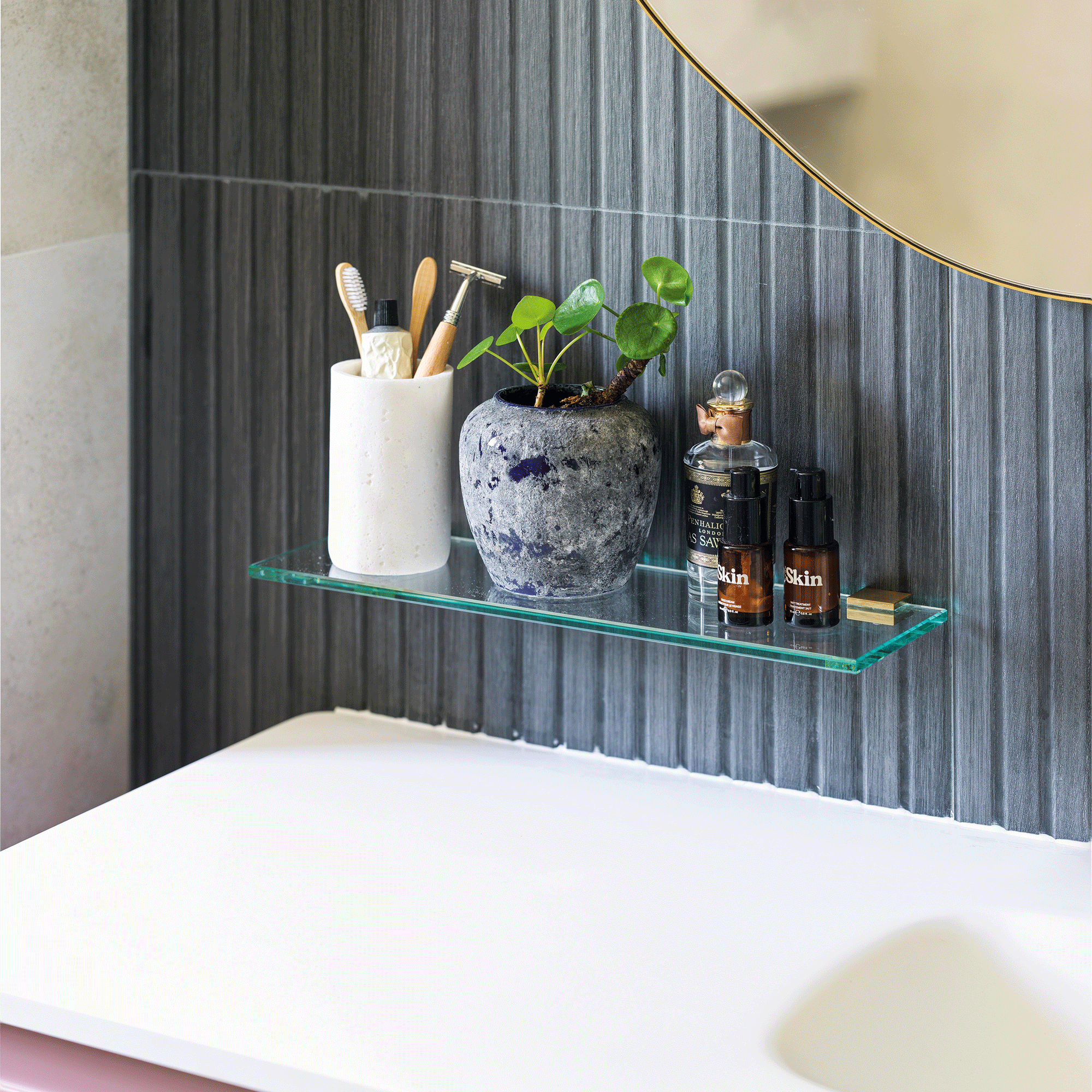 close up of a glass shelf in a bathroom with charcoal pencil wall tiles
