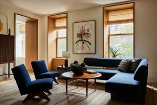 A living area with deep blue armless chairs and an L-shaped sofa.