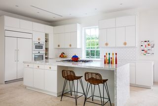 An all-white kitchen with red accessories