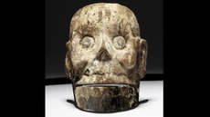 a wood mask carved to look like a human skull