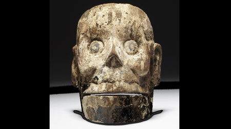 a wood mask carved to look like a human skull