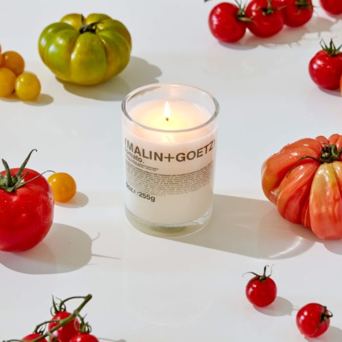 lit candle on surface with tomatoes