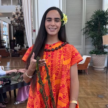 A woman holding a lei wearing an orange dress