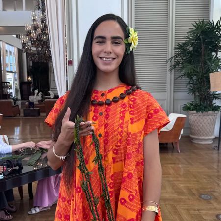 A woman holding a lei wearing an orange dress