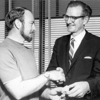 Apollo 14 astronaut Edgar Mitchell (left) presents Rev. John Stout of the Apollo Prayer League with a package of flown lunar bibles in 1971.