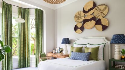 Bedroom accent wall ideas featuring round wicker decor in a neutral scheme with bright green and blue accents and drapes.