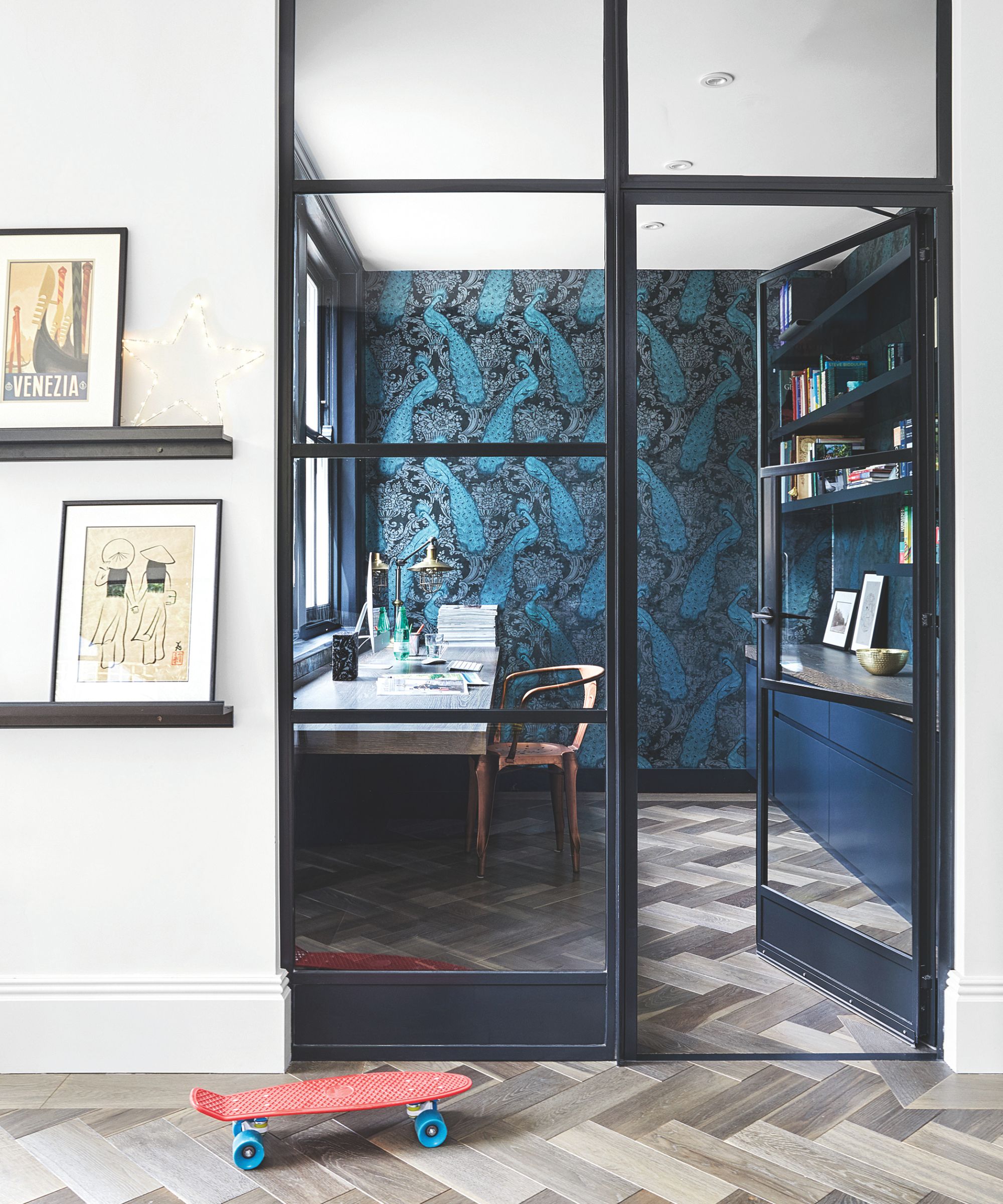 Blue study with glass doors, patterned wallpaer and decorated shelving