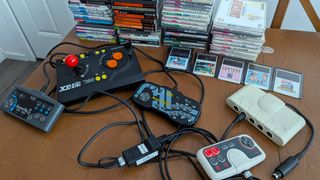 Collection of PC Engine and Turbografx 16 games next to controllers and single game cards