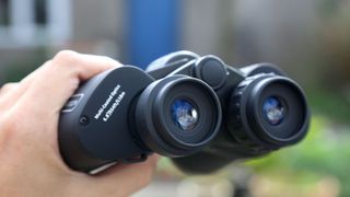 Image shows a hand holding Celestron UpClose G2 10x50 binoculars.