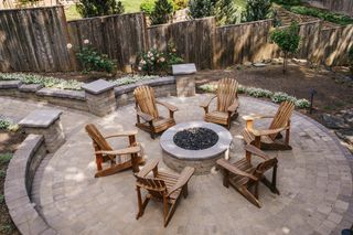 Outdoor fire pit with wooden chairs in backyard