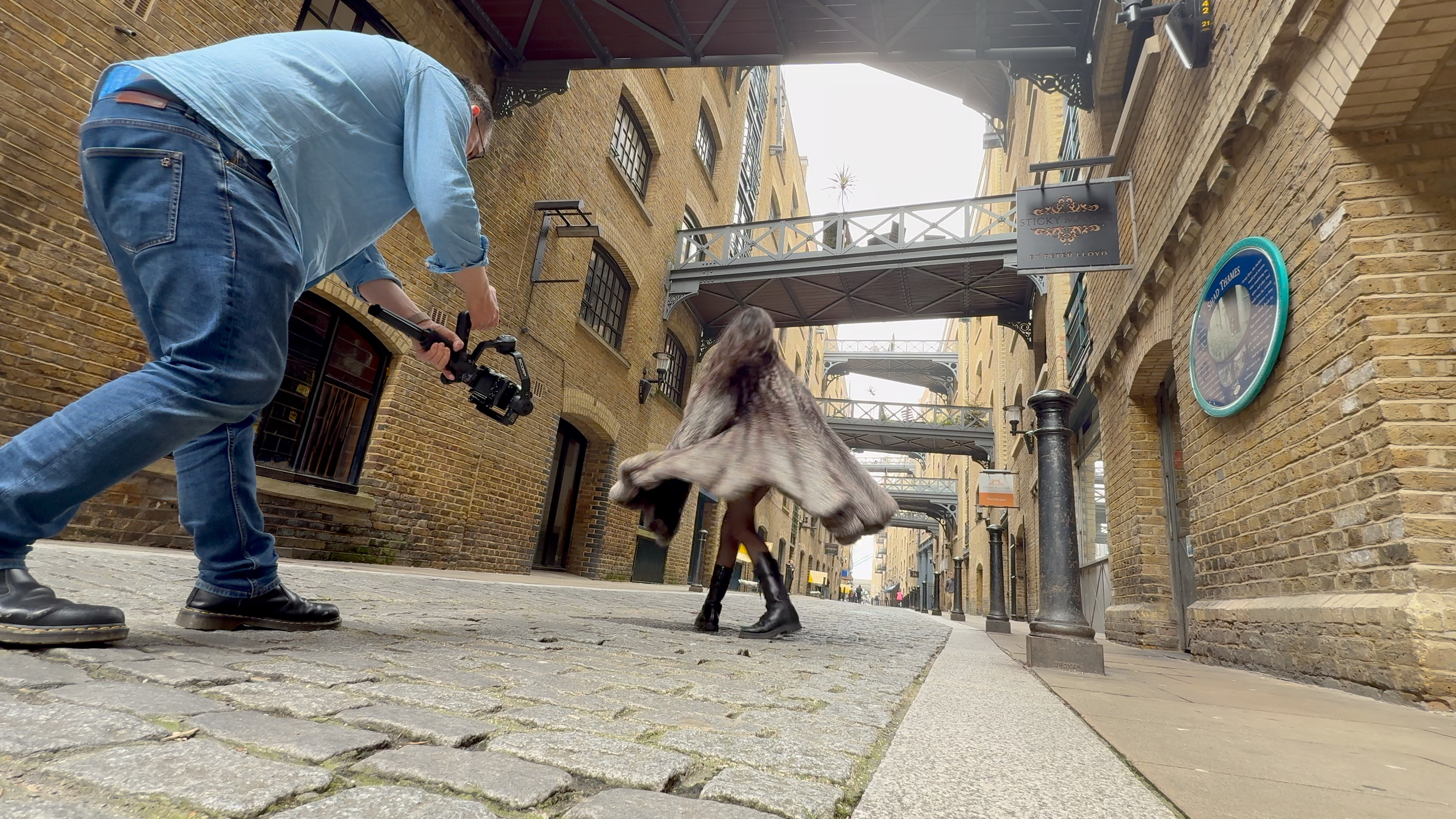 Low-angle view of a man filming a spinning subject with a gimbal in a narrow street