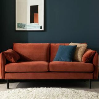 Rust coloured sofa in a dark blue living room