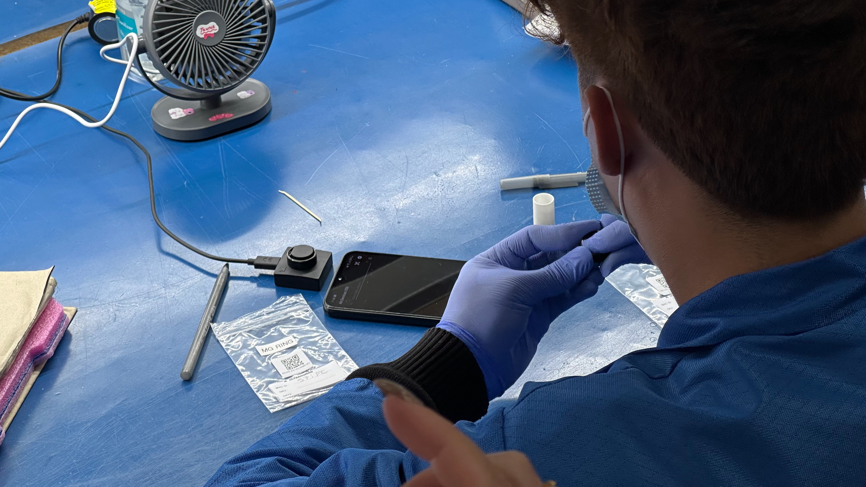 An Ultrahuman factory worker QC testing a smart ring's software before the casting process.