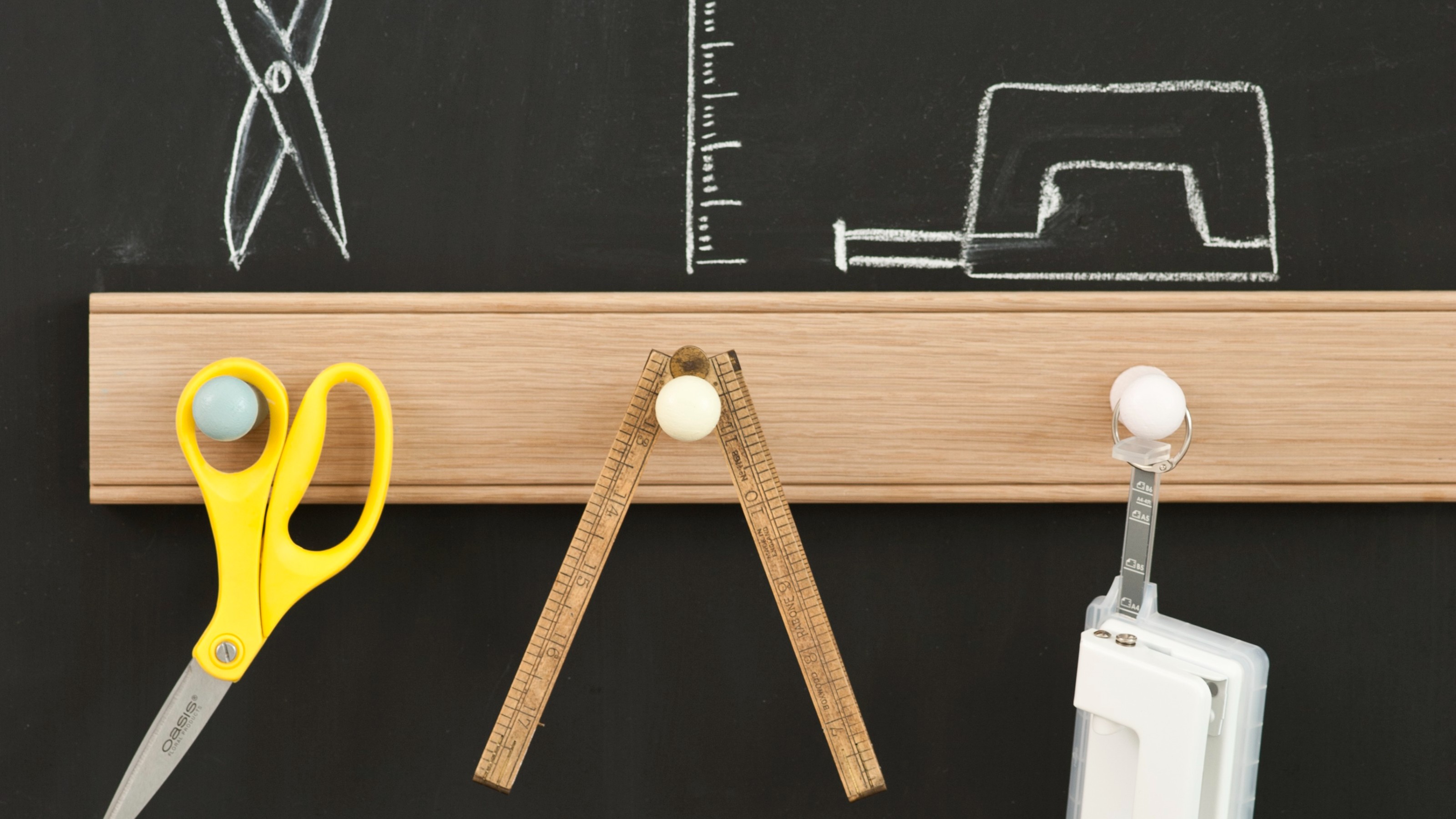 A blackboard wall with a peg rail used to hang DIY tools