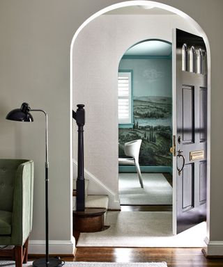 arched doorway with view to front door and room with mural