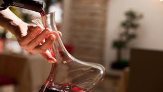 person pouring wine into carafe