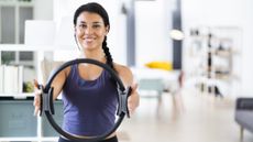 Woman holding a Pilates magic circle, a 15-inch diameter ring with handles on opposing sides