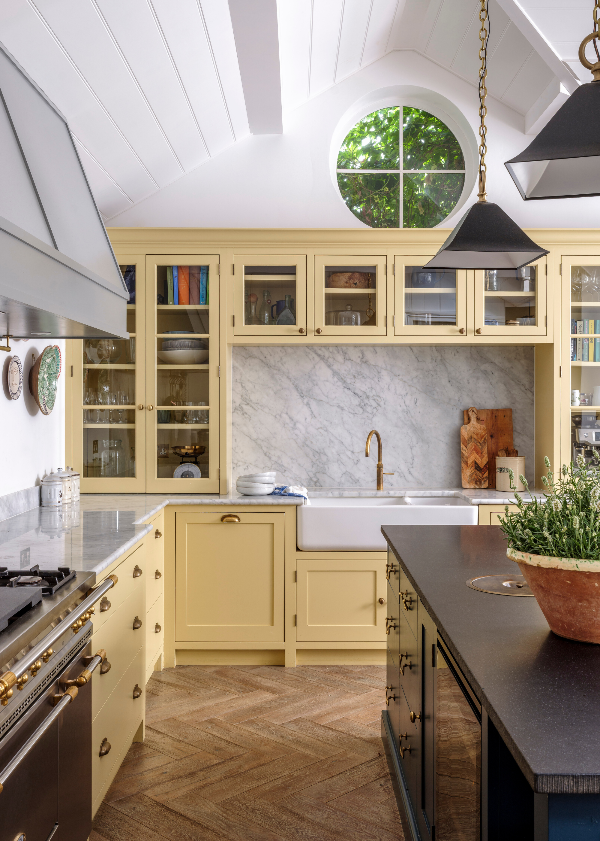 A traditional light yellow kitchen with a vaulted ceiling that is panelled and a port window at the highest point