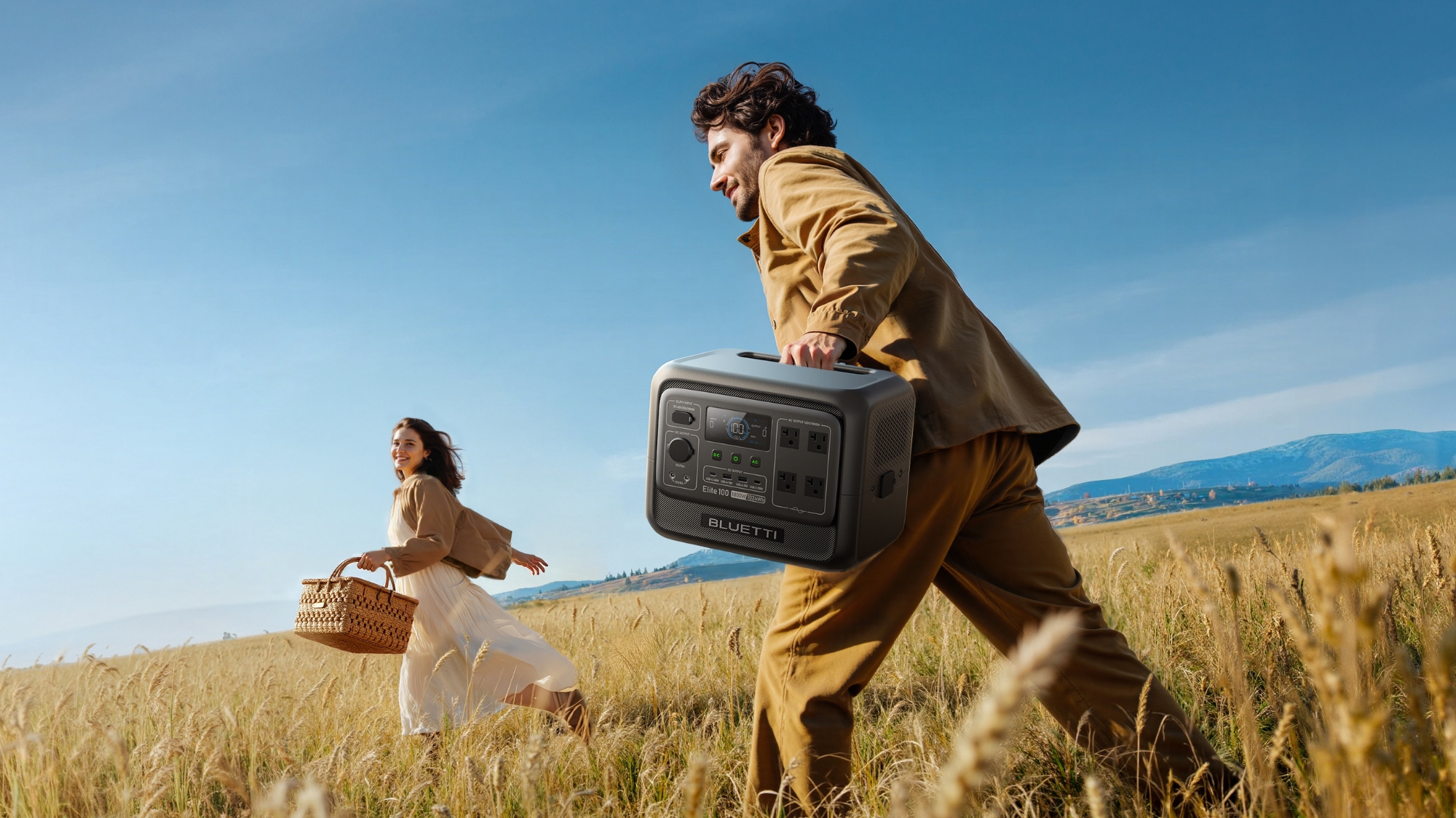 2 people running through a field of wheat with a bluetti generator