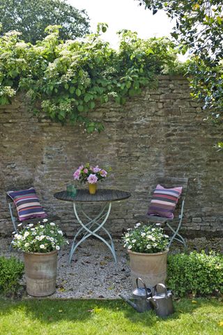 Stone wall with a bistro set dining space and striped cushions