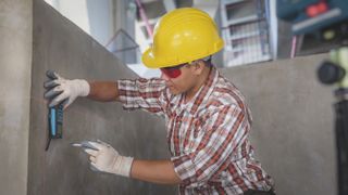 Man in hard hat holding one of the best laser levels against a concrete block