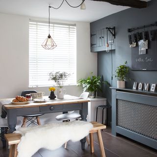 room with grey wall and dining table and bench and faux fur rug