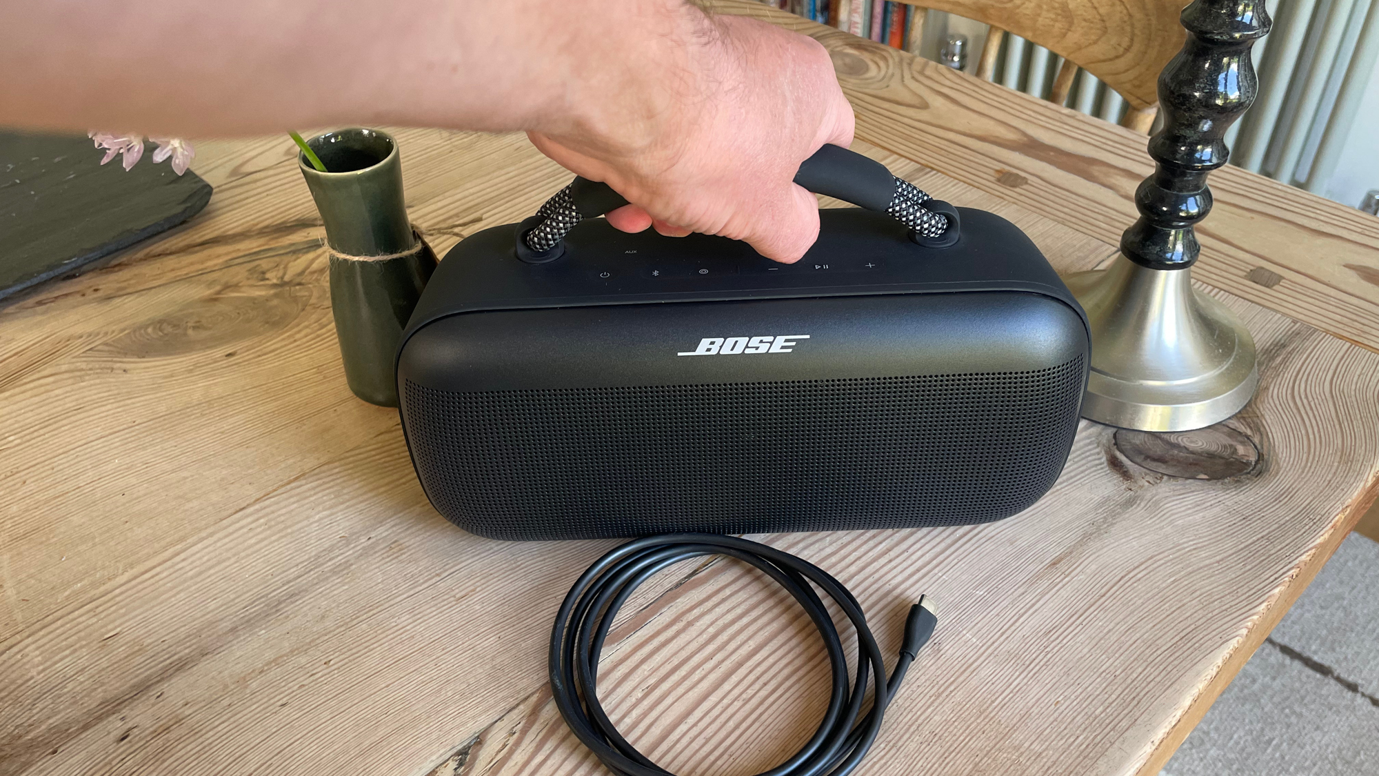 Bose SoundLink Max being held by carry handle above kitchen table