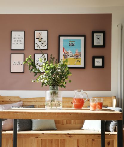 Pink wall with gallery wall of art prints in a dining area 