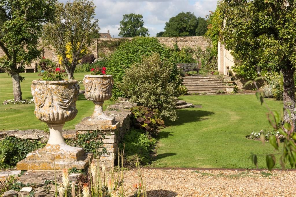 The gardens at Luckington Court with stone plant pots to the left hand side