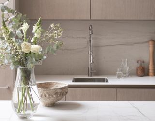 A vase of flowers including eucalyptus and white roses in a neutral kitchen