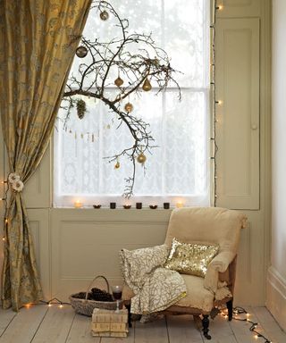 Beige armchair in front of a window with Christmas decorations and Christmas lights on the floor